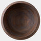 A round dark brown wooden bowl with a visible natural wood grain pattern, photographed from directly above on a light gray background.