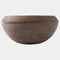 A rustic wooden bowl with a wide rim and a textured, weathered finish, shown against a plain light gray background.