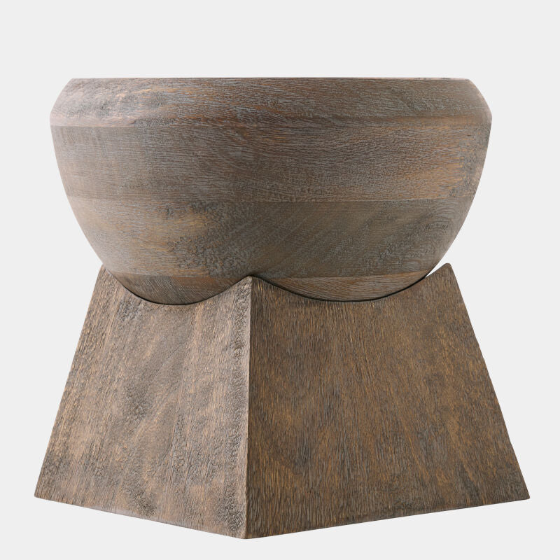 A rustic wooden pedestal stool with a wide, rounded bowl-like seat and a geometric, tiered base, shown against a plain light gray background.