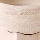 Close-up of a light natural wood bowl showing the grain texture and curved rim, resting on a matching wooden surface.