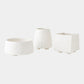 Three white textured planters of different shapes on a light gray background