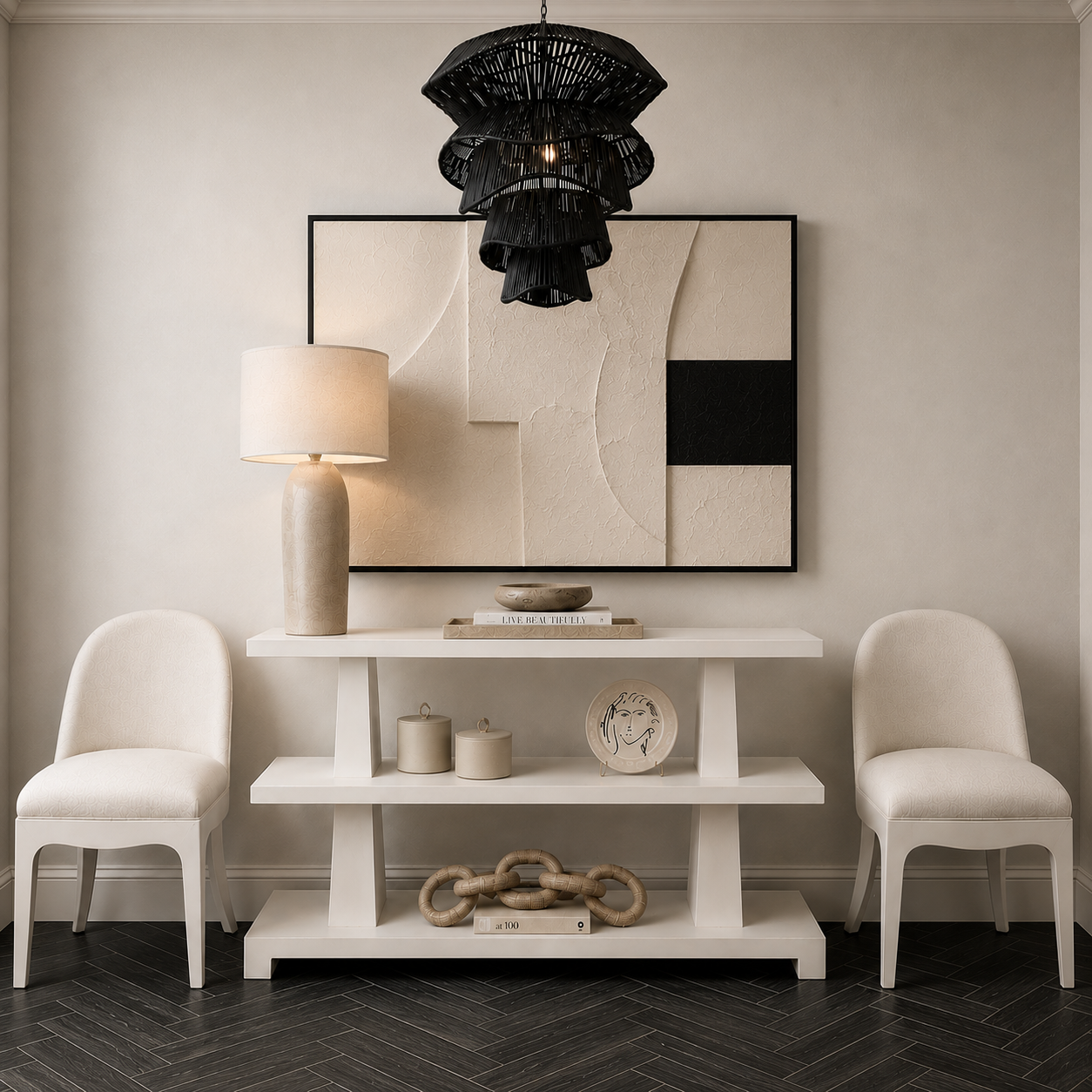 A styled interior scene with a white console table, two cream upholstered chairs, a black woven pendant light, a table lamp, decorative objects, and a large abstract wall artwork on a beige wall.