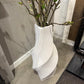 White vase with branches on a gray floor