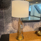 Decorative lamp on a table with a mirror reflecting people in a room.