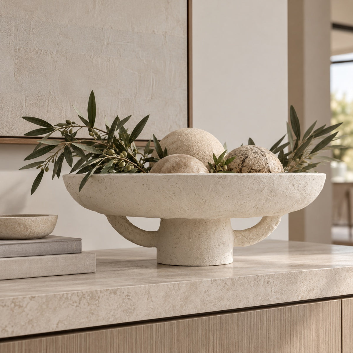 Marie Mache Bowl styled on console table with decorative balls and branches inside of it 