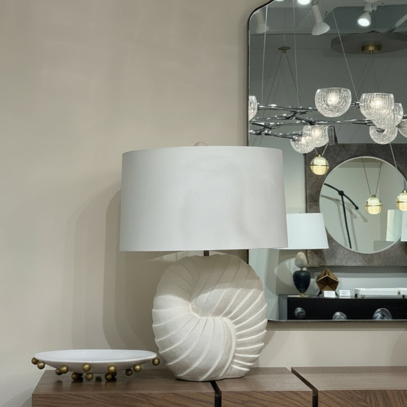 Decorative lamp on a wooden cabinet with a mirror and chandelier in the background