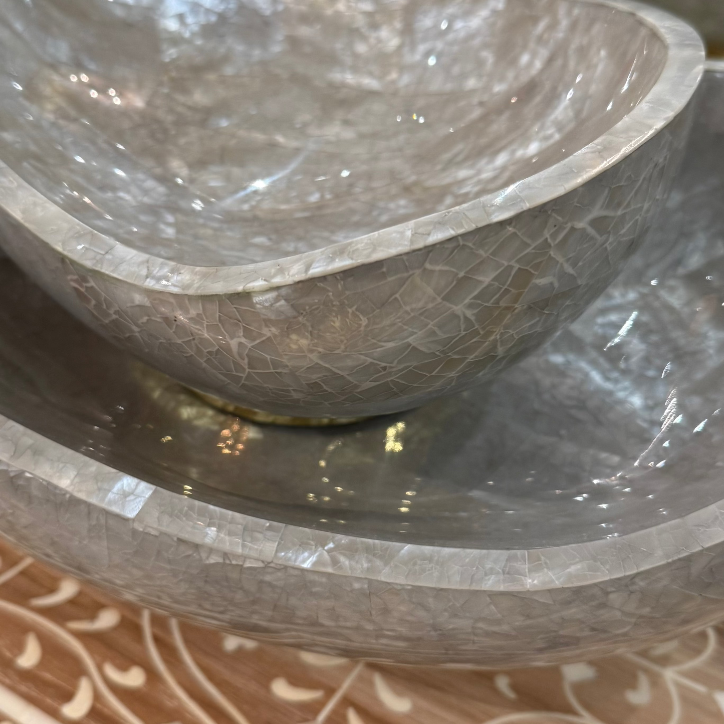 Two stone bowls stacked on a wooden surface with intricate carvings