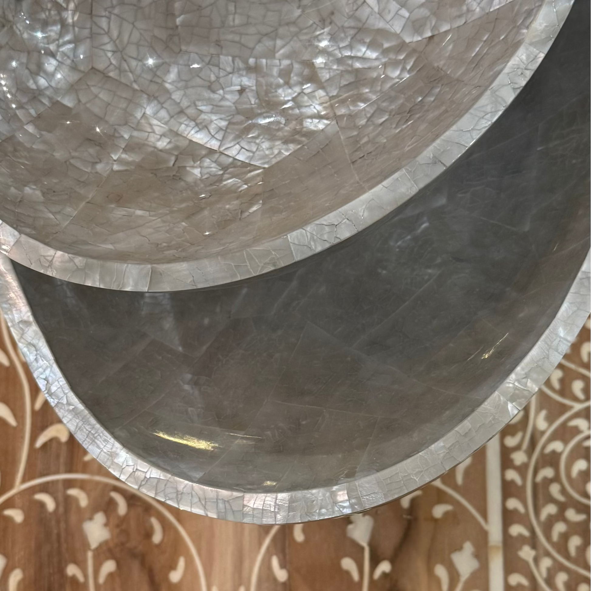 Decorative stone bowl with mosaic pattern on a wooden surface with intricate carvings