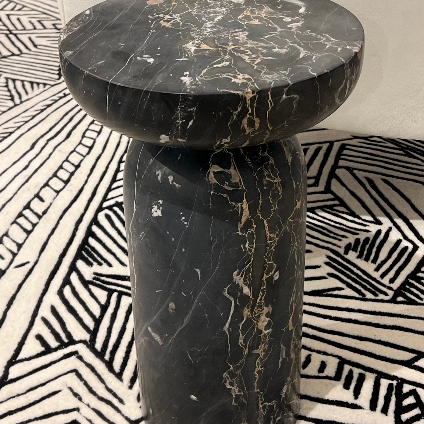 Black marble side table on a patterned rug