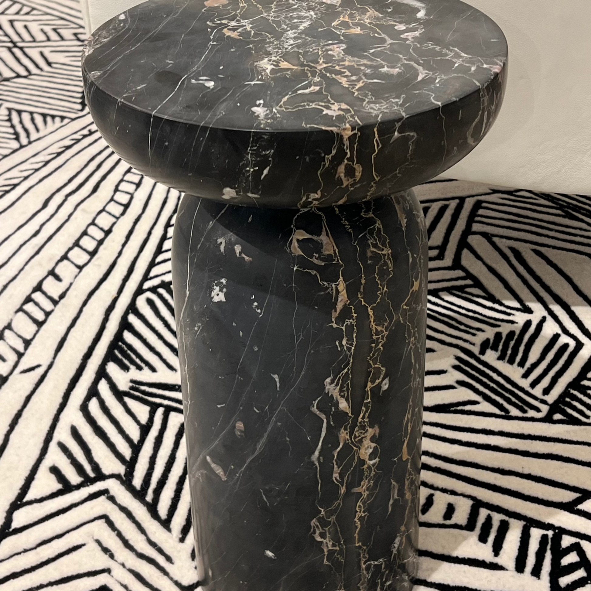 Black marble side table on a patterned rug