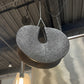 Textured pendant light fixture hanging in a room with reflective floor.