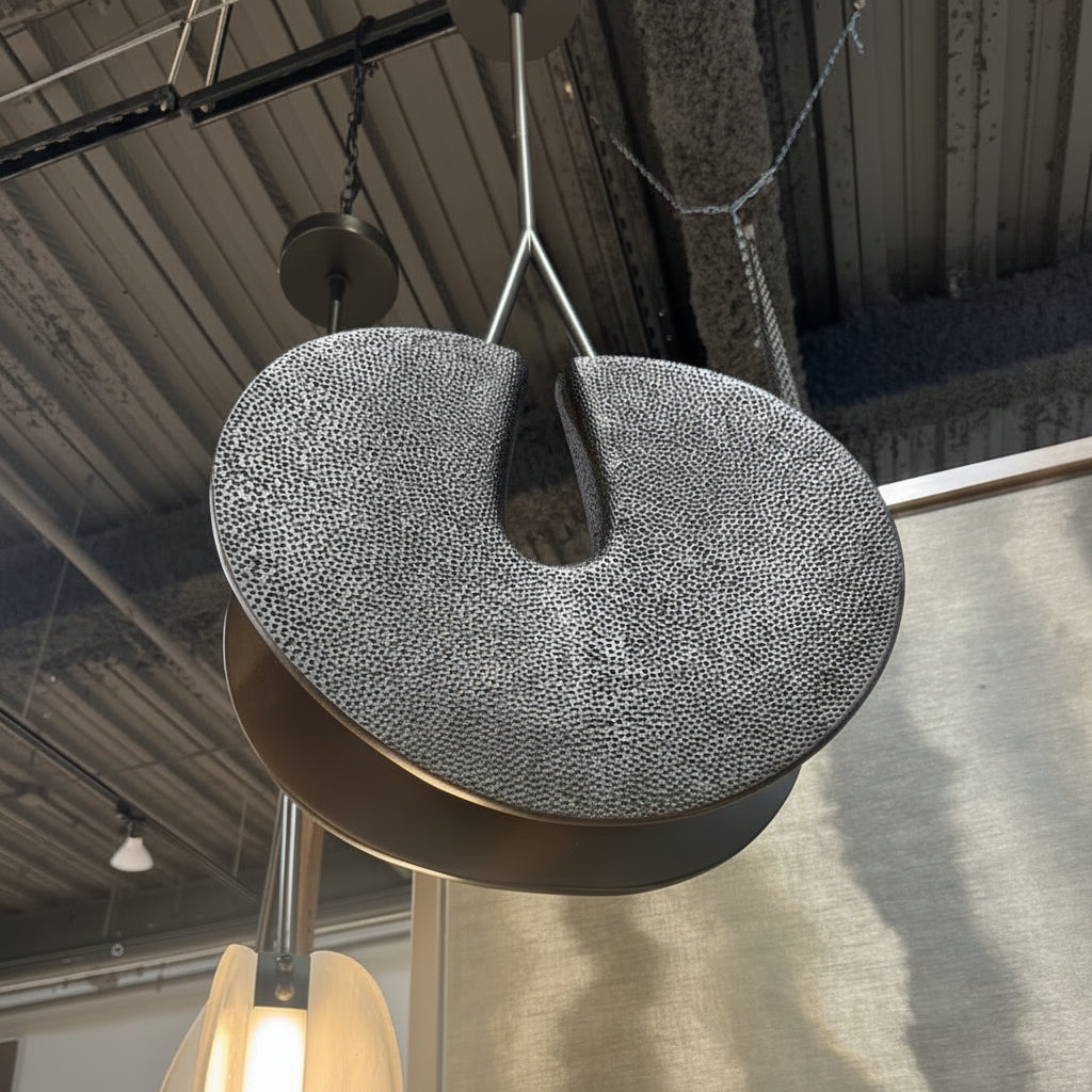 Textured pendant light fixture hanging in a room with reflective floor.