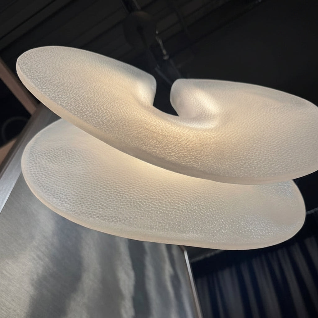Three white textured objects stacked on a reflective surface