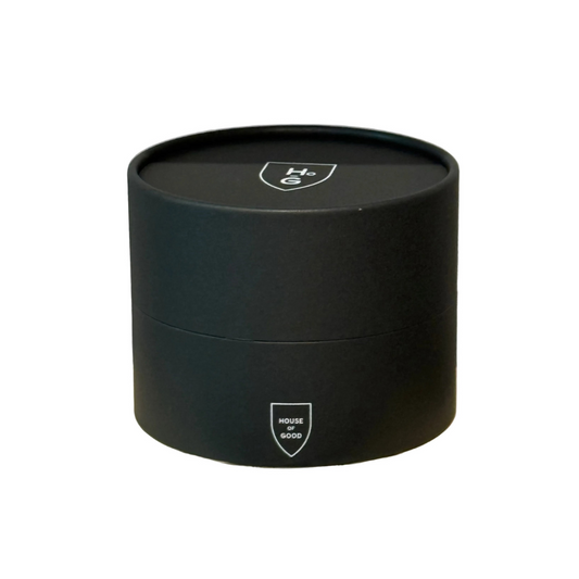 Black cylindrical candle container with a logo on a white background