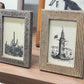 Two framed pictures on a wooden surface with textured frames.
