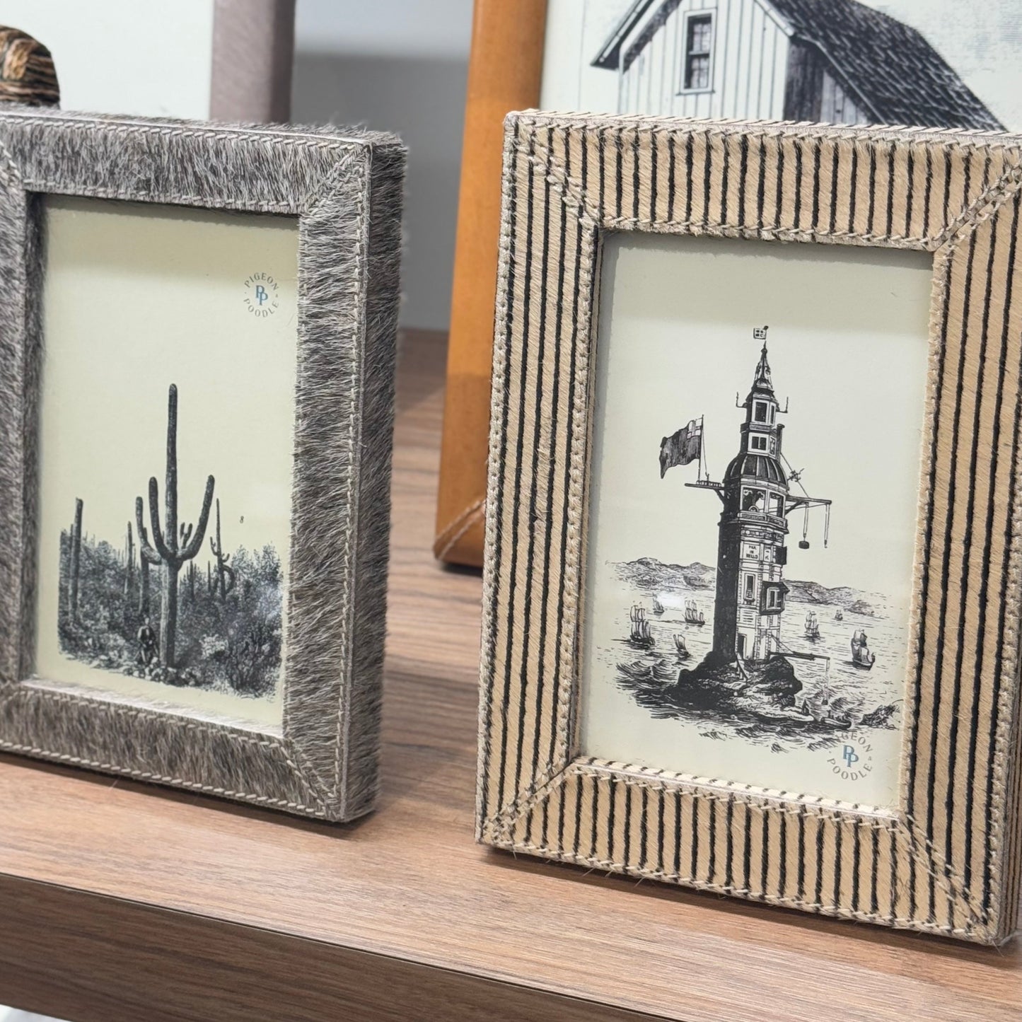 Two framed pictures on a wooden surface with textured frames.