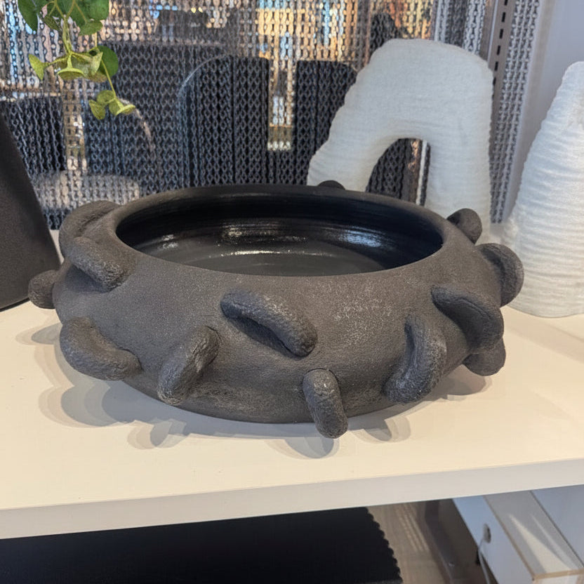 Decorative rpund-shaped bowl on a table with a reflective background