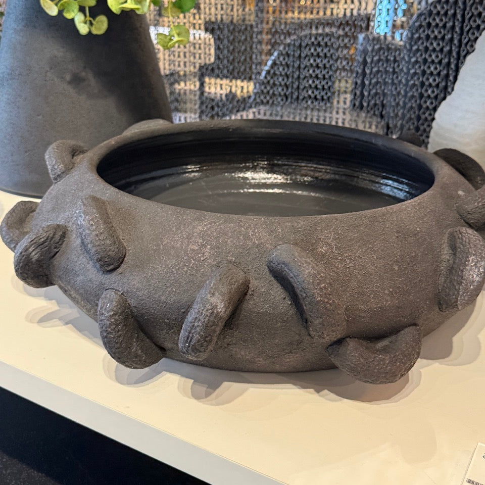 Decorative black pot with unique design on a surface