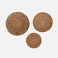 Three round woven seagrass placemats in different sizes arranged on a light gray background.
