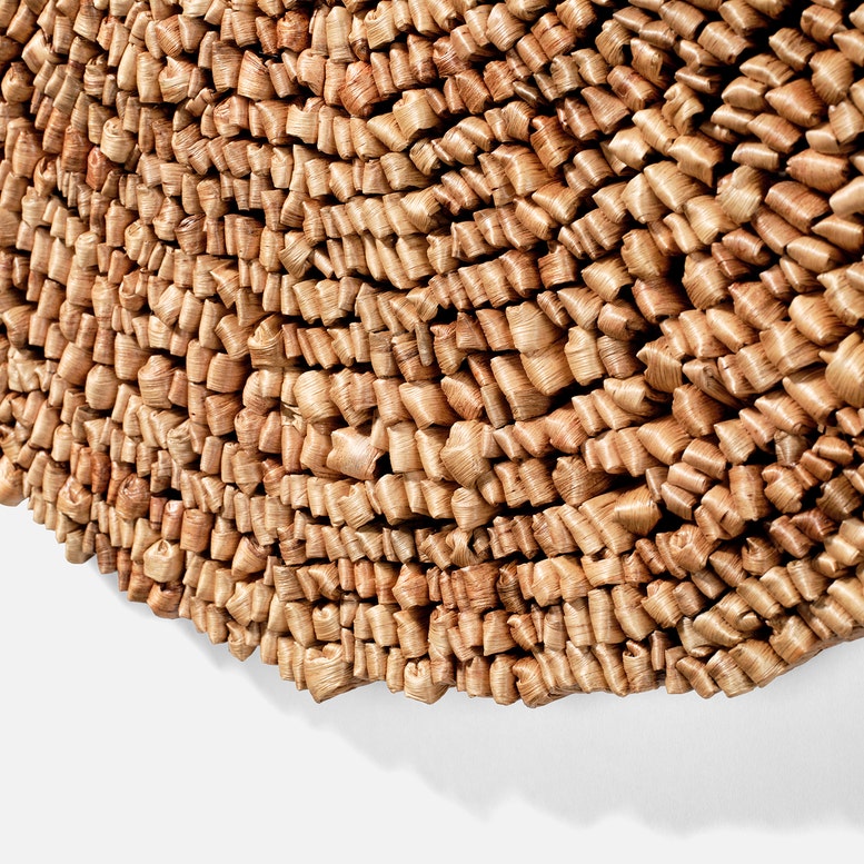 Close-up of a textured brown wall art on a white background