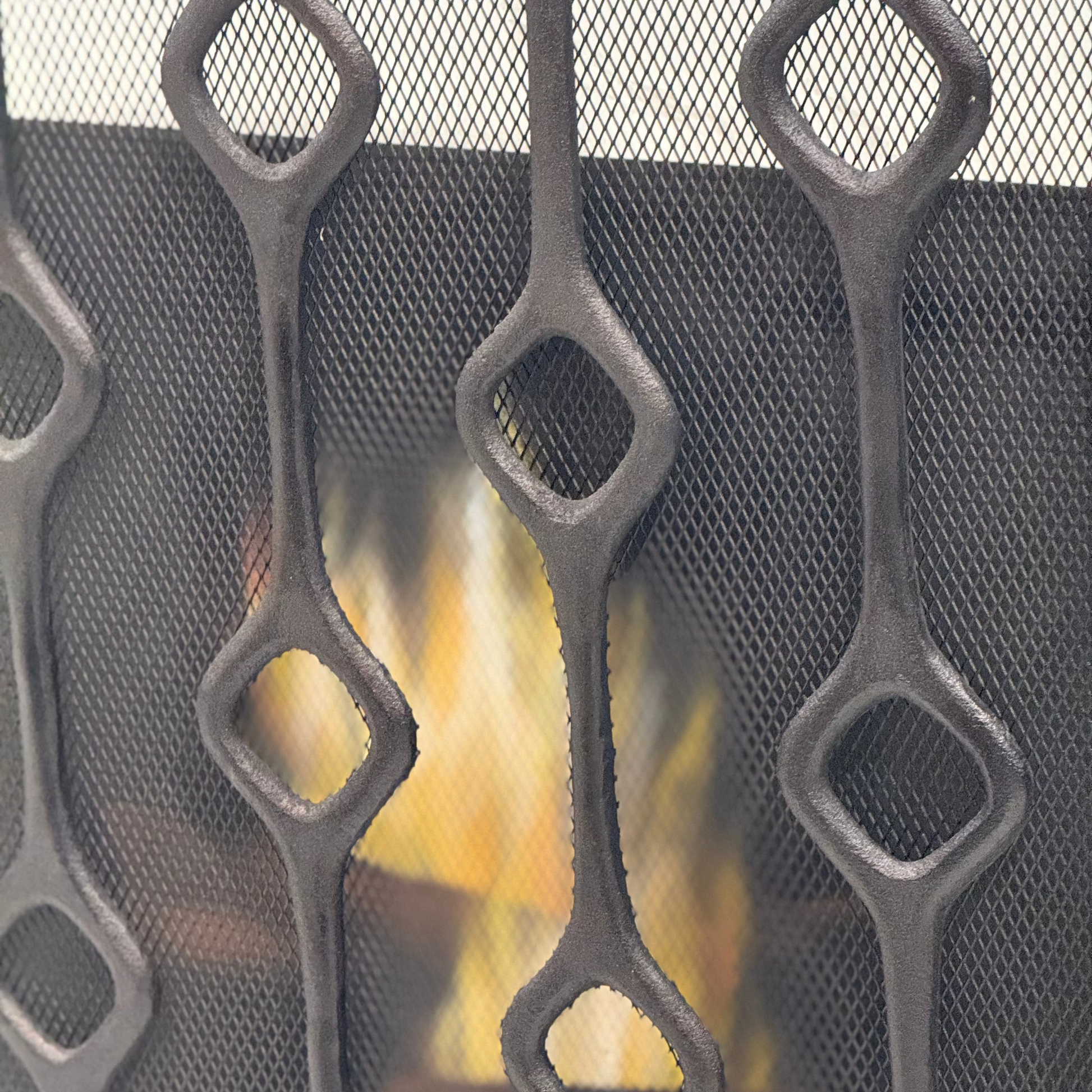 Decorative fireplace screen with mesh design and visible fire.