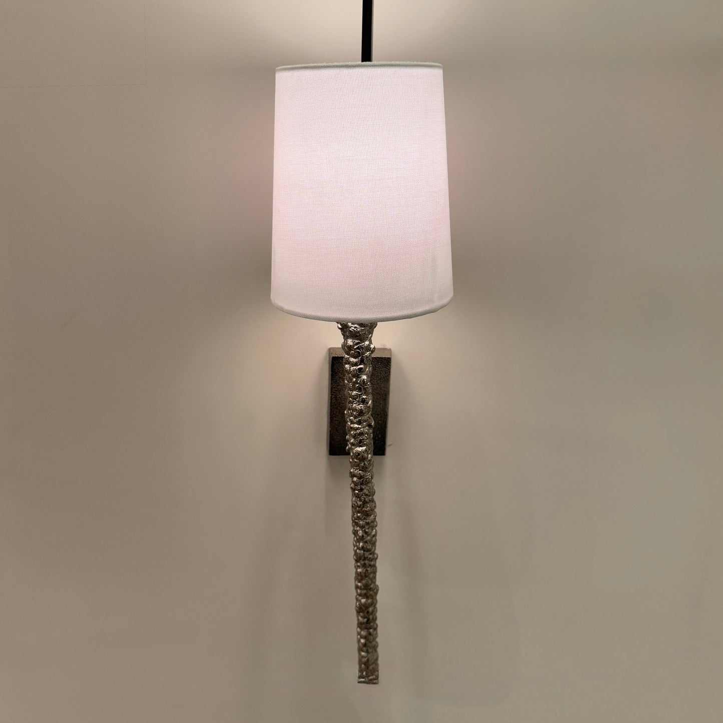 Wall-mounted lamp with a white shade on a plain wall