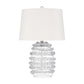 A table lamp with a white fabric drum shade and a clear ribbed glass base, shown against a plain white background.