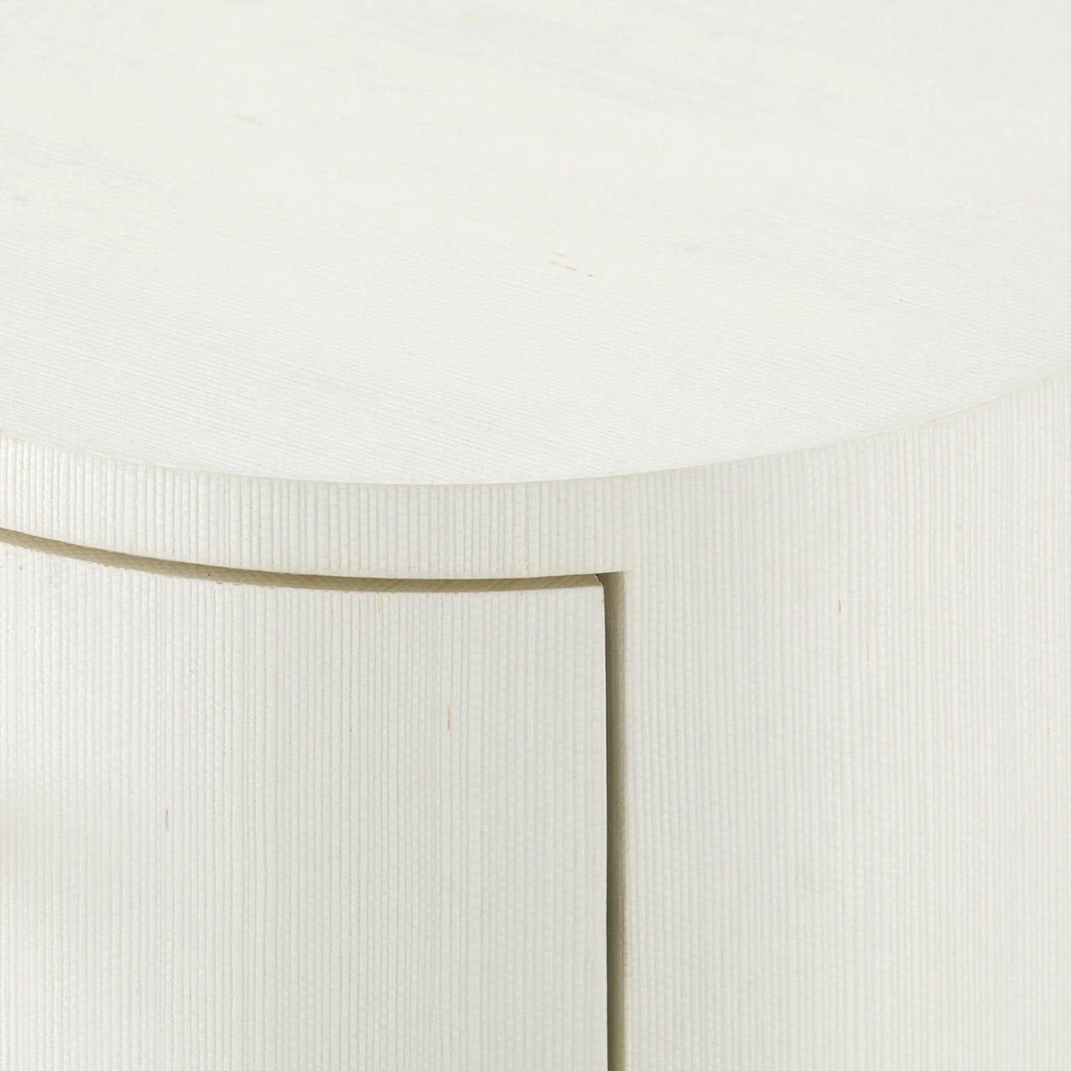 Close-up detail of a white textured cabinet or sideboard with a curved front panel and a visible seam.