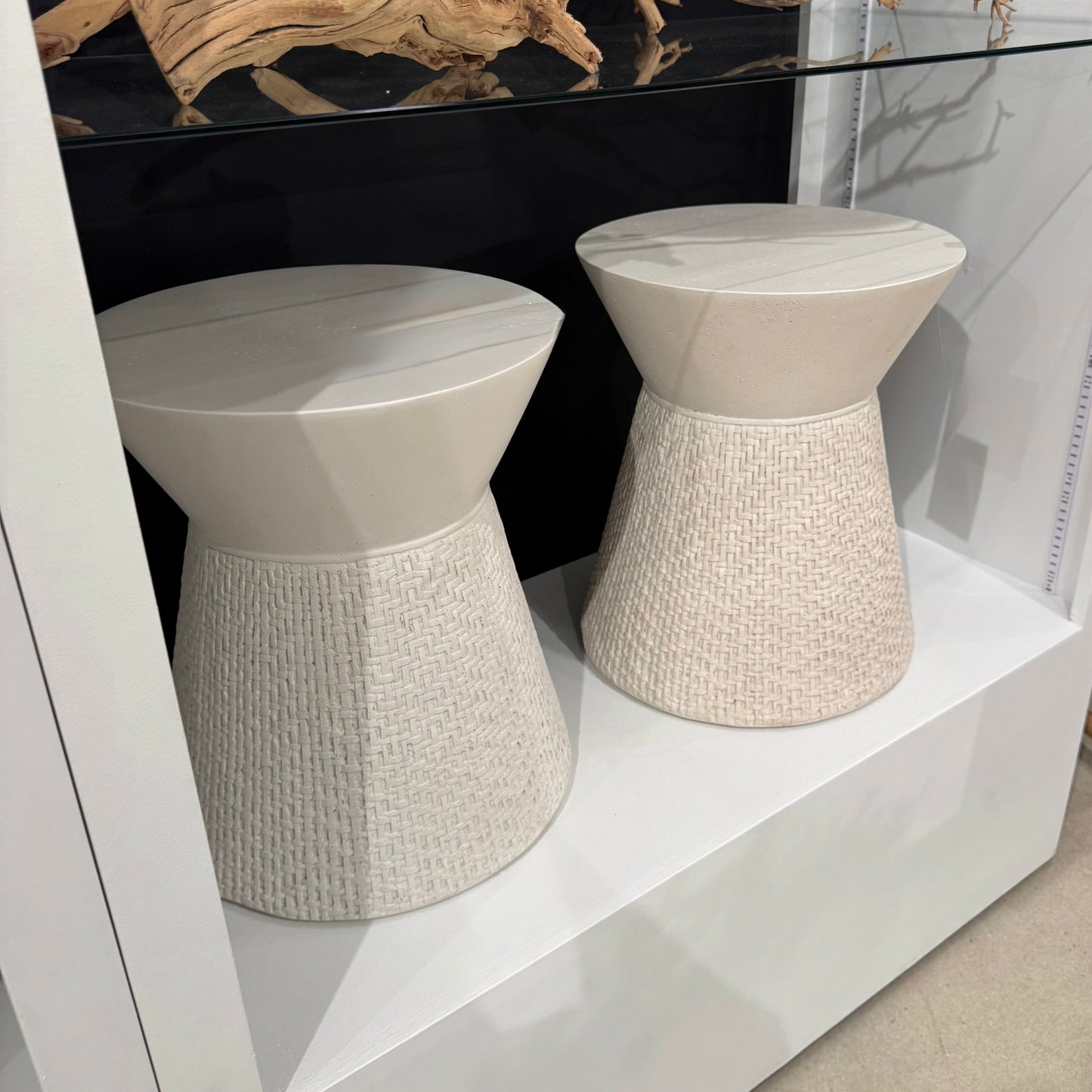 Two white textured stools on a white platform with a black background