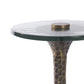 Round glass table with textured bronze base on a white background