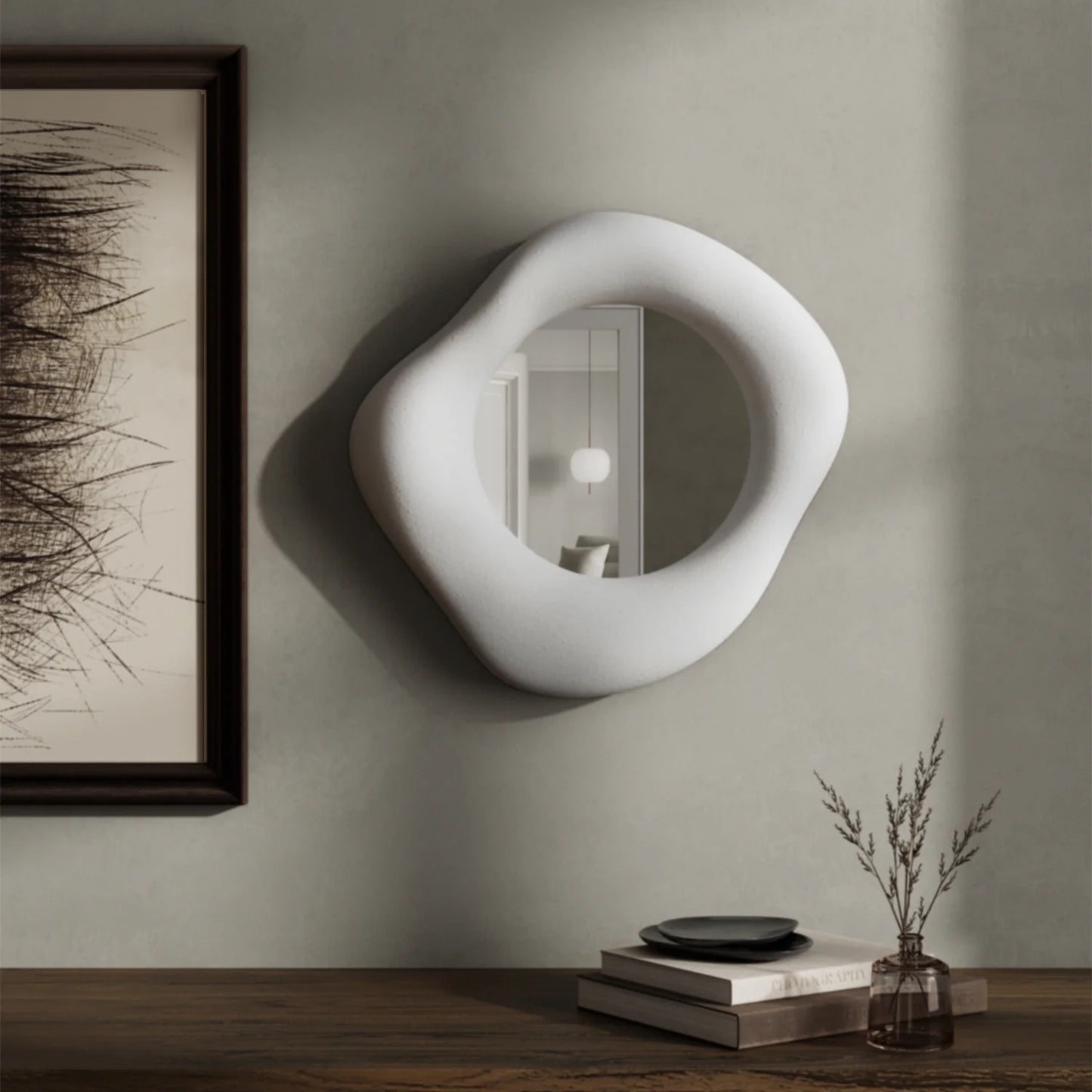 Modern white wall mirror on a neutral wall with decor items below.