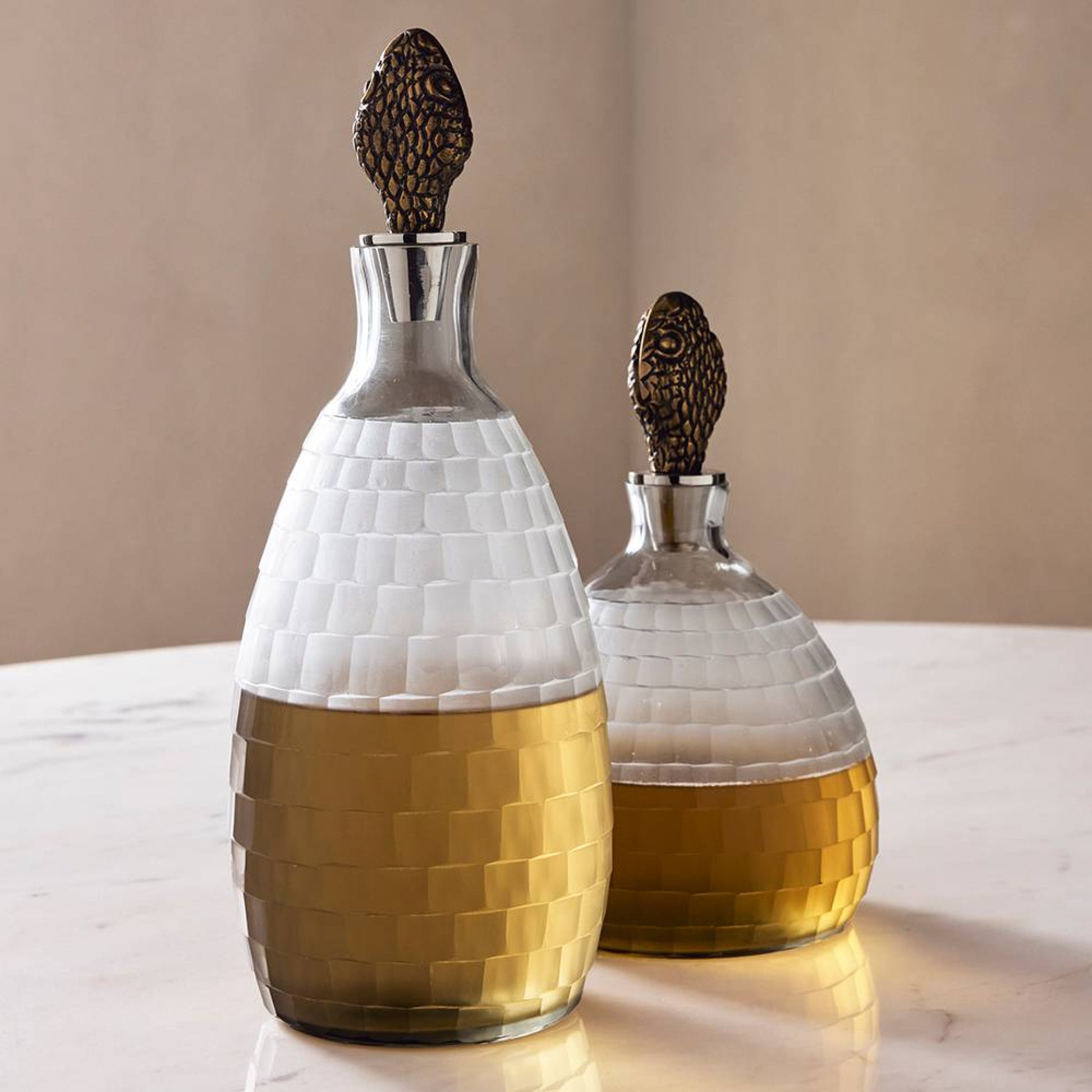 Two glass decanters with woven design and bronze stoppers on a beige surface.