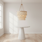 Chandelier hanging above a round table in a bright room with wooden floor and white walls.