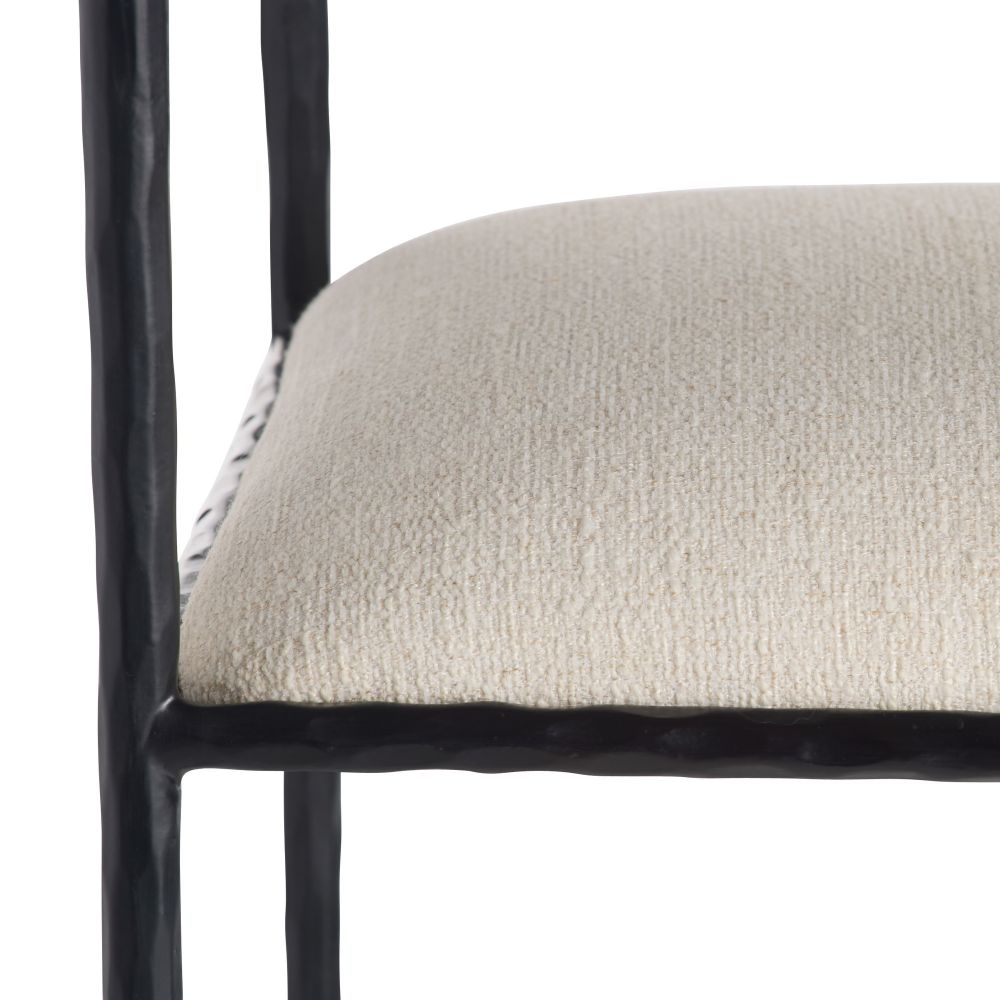 Close-up of a chair with a textured beige cushion and black metal frame on a white background