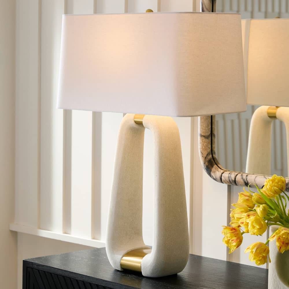 Decorative table lamp with a white shade and marble base on a dark surface.