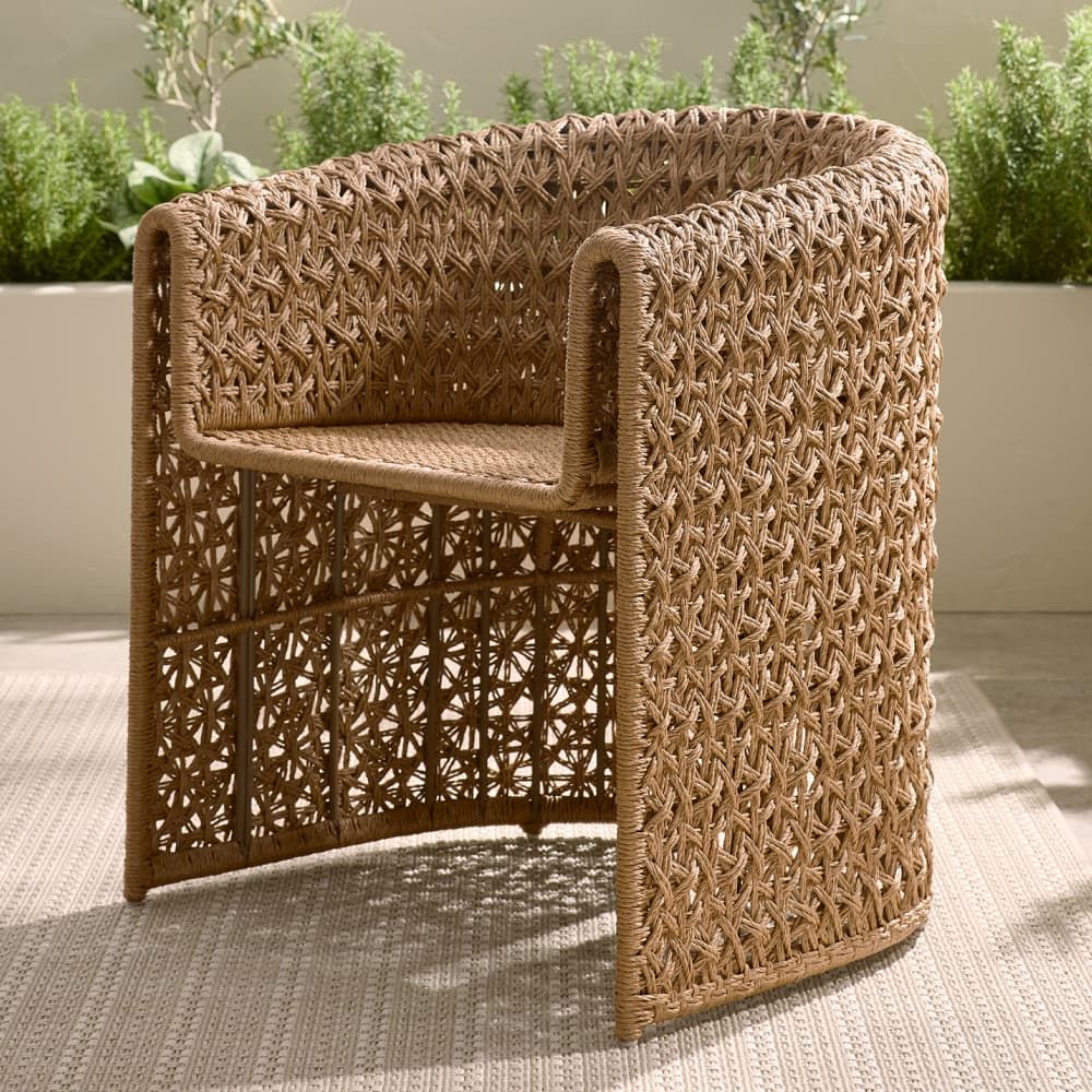 Woven wicker chair on a patio with plants in the background