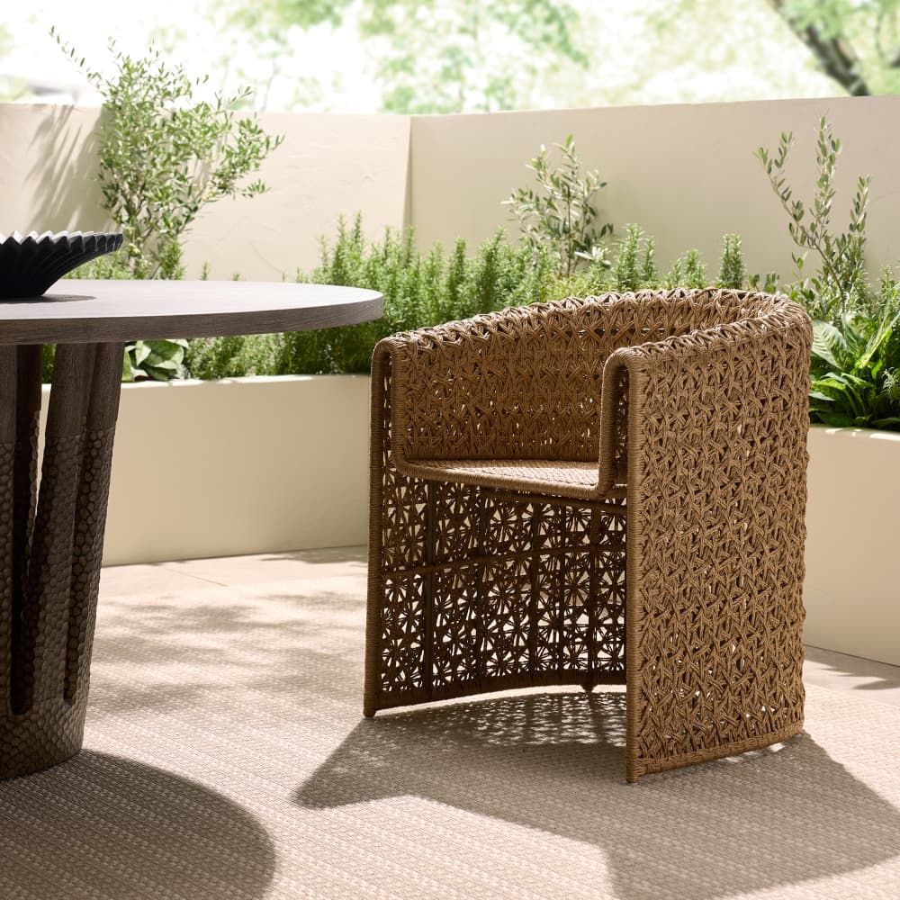 Woven chair and table on a patio with plants in the background