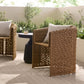 Woven outdoor chairs with patterned backrests on a patio with plants in the background