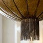 Close-up of a decorative light fixture with chain tassels against a neutral background