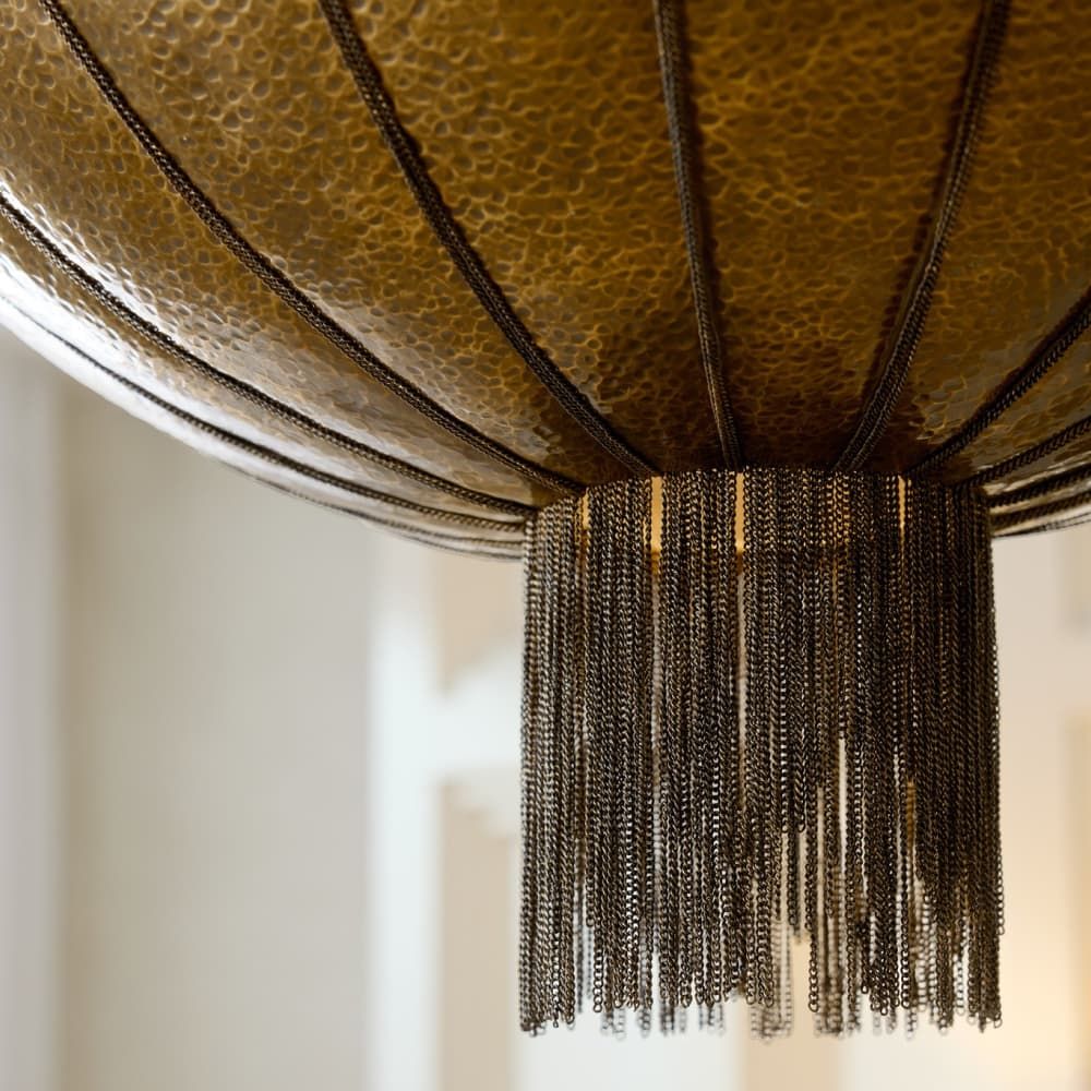 Close-up of a decorative light fixture with chain tassels against a neutral background