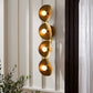 Gold wall sconce with three lights against a white paneled wall.