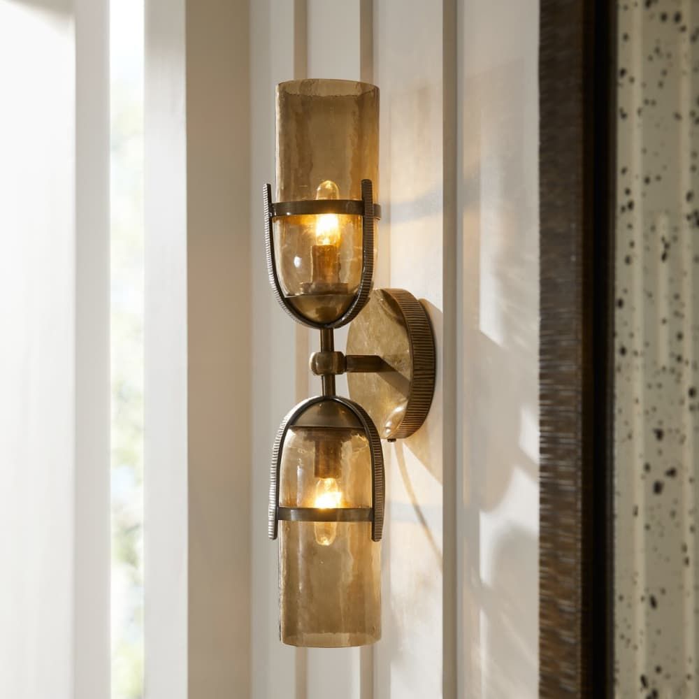 Decorative wall sconce with glass shades on a neutral wall.
