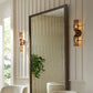 Decorative mirror with a textured frame on a wall with two wall sconces.