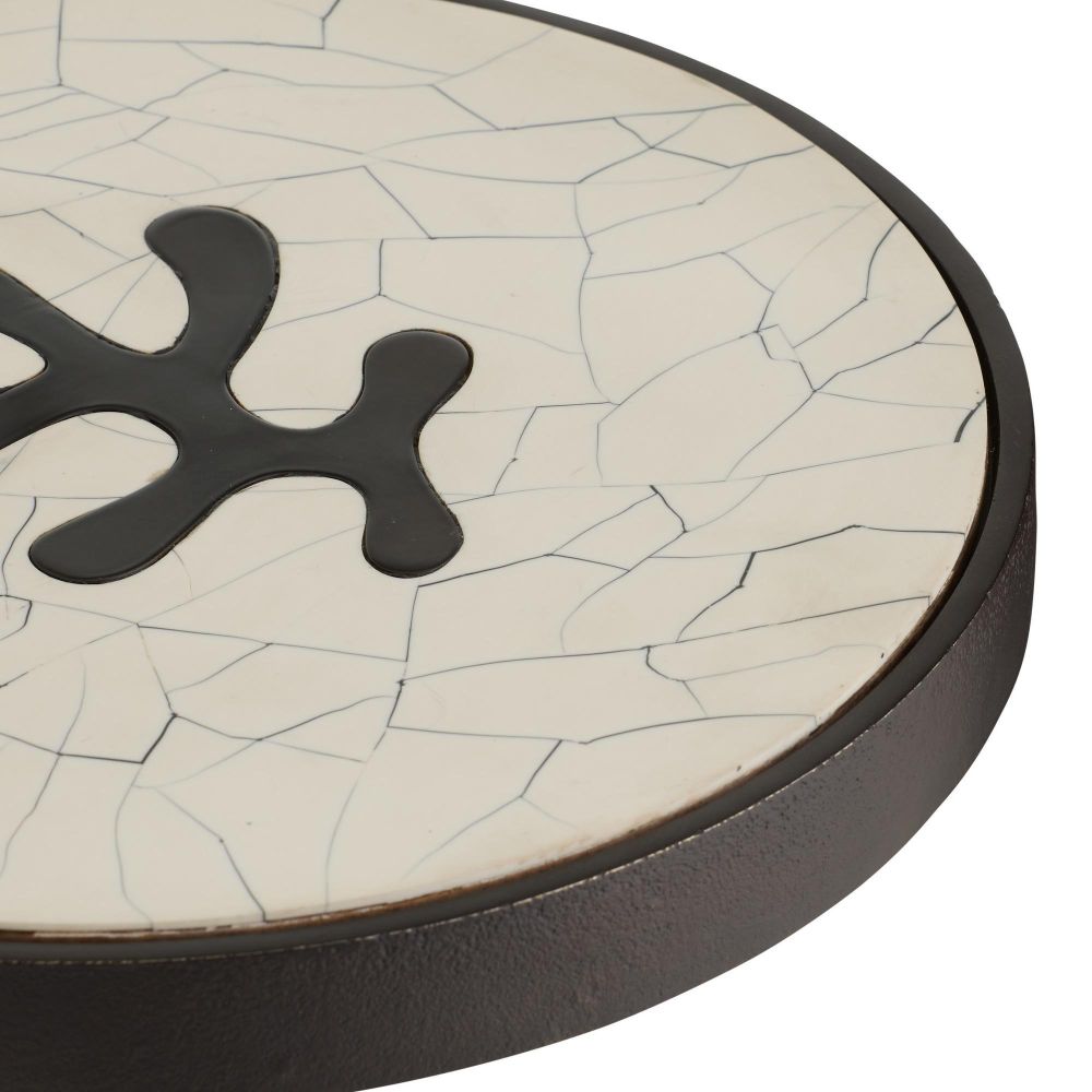Round ceramic coaster with cracked white surface and black central design on a white background