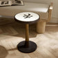 Small round table with a black base and white top in a room with a bench and open book.