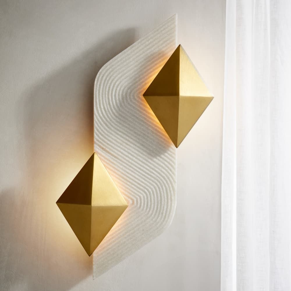 Gold geometric wall sconces on a textured white wall