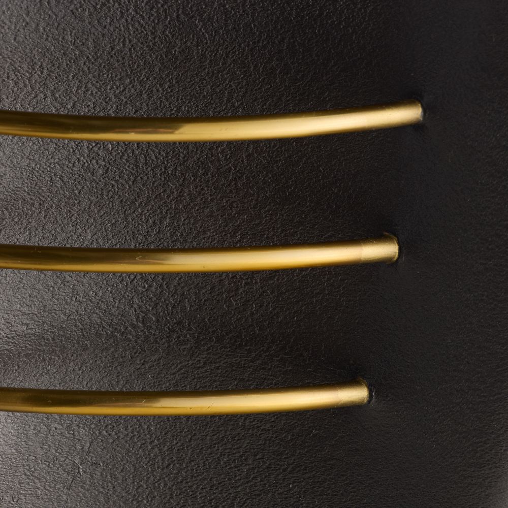 Three gold bracelets on a black leather surface