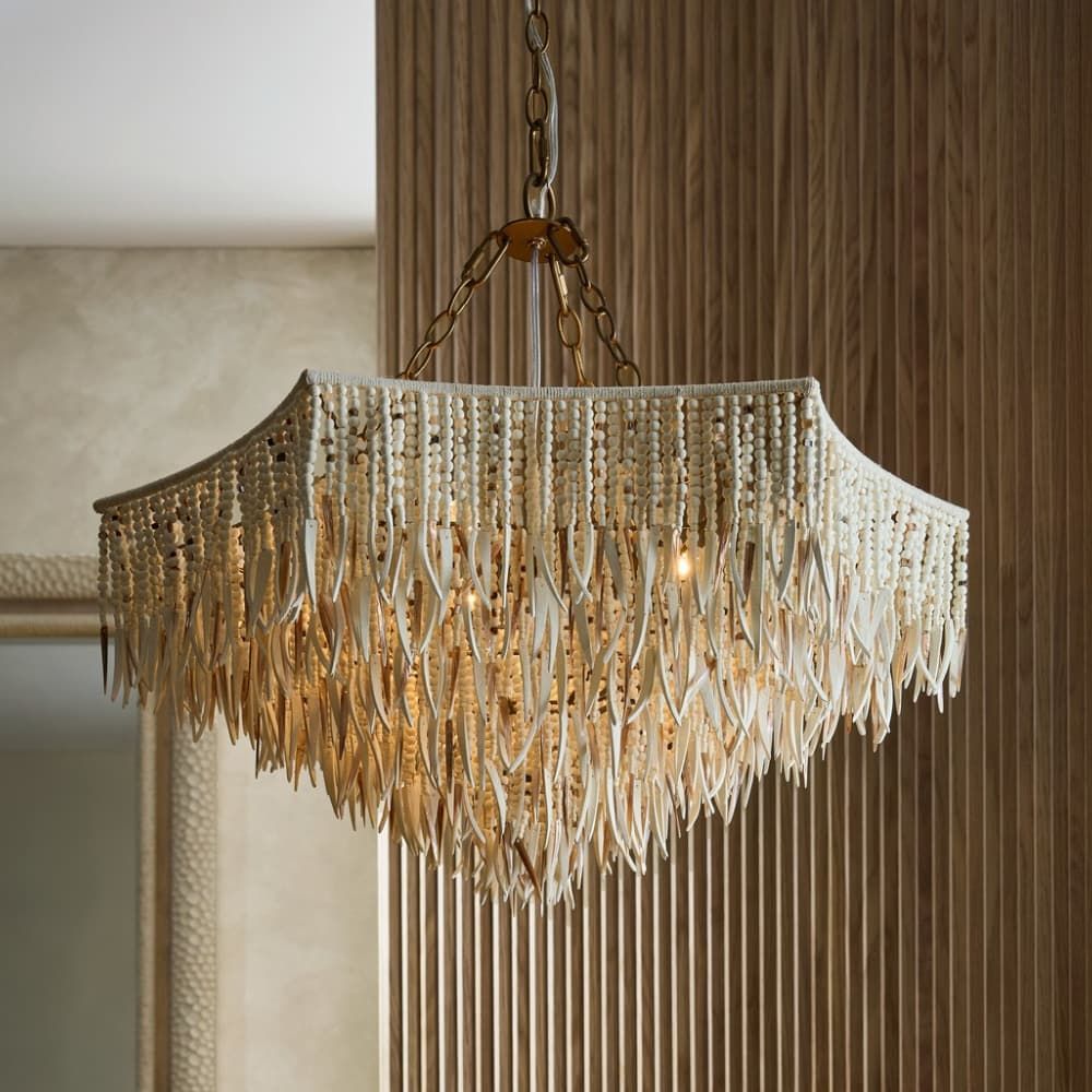 Chandelier with crystal fringes hanging in a room with neutral walls.