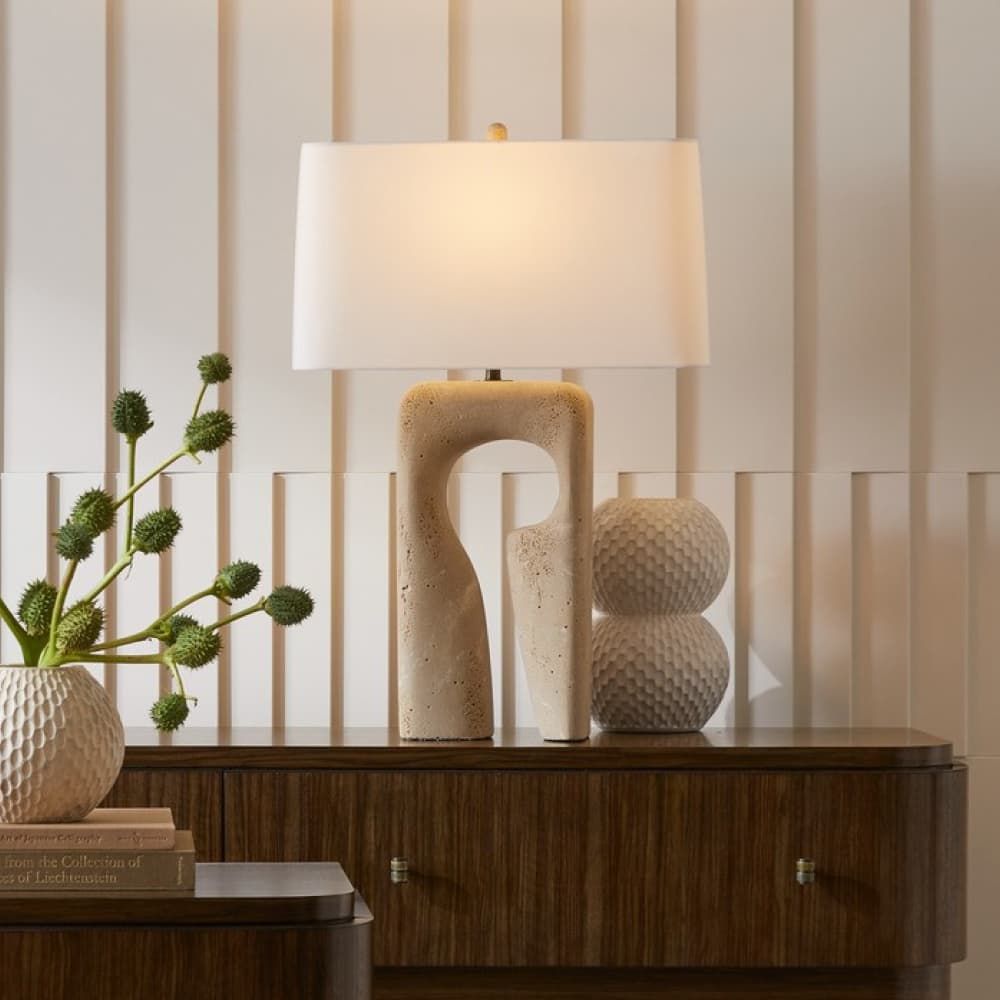 Decorative lamp with a textured base on a wooden surface against a striped wall.