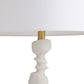 Lamp with a textured white base and gold fixture on a white background